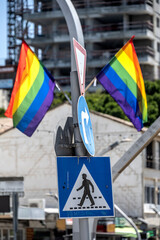 Two pride flags over pedestrian sign on the street in Israel.