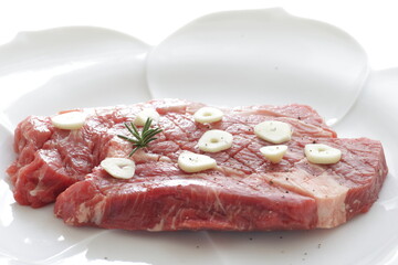Seasoning beef steak, garlic and pepper on plate