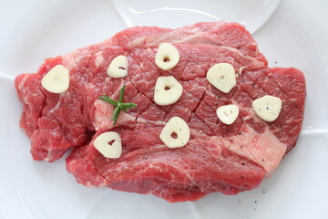 Seasoning beef steak, garlic and pepper on plate
