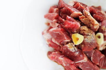 Seasoning cut beef steak, garlic and pepper on plate