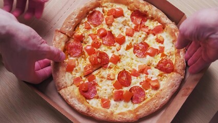 Top view of human hands taking pizza slices with hot chorizo from the box