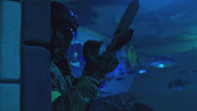 Close up shot of portrait of special force soldier or swat man . Swat man with automatic weapon loading bullet magazine, aiming and looking around . During military operation . Slow Motion