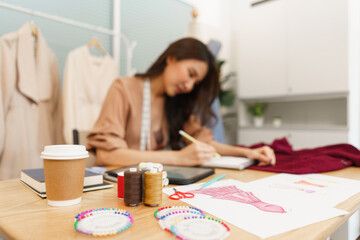 Obraz na płótnie Canvas Fashion design concept, Asian female fashion designer sketching new clothes collection on notebook