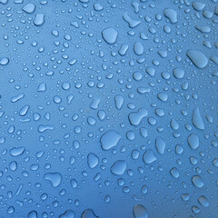 A drop of water on the hood of the car. Water beads after rain or car wash on blue paint surface.