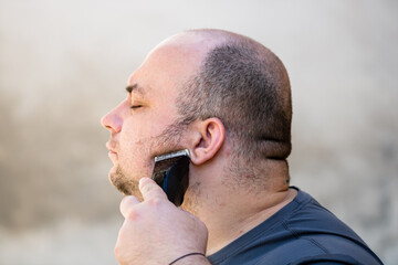 Male shaving or trimming his beard using a hair clipper or electric razor