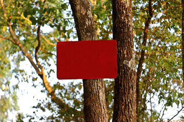 red sign placed on tree at daytime