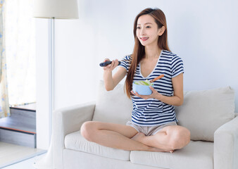 Happy young woman watching  TV at home