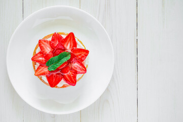 Strawberry tart with mint leaf, sweet cake dessert, on white wooden board background, top view, space to copy text.