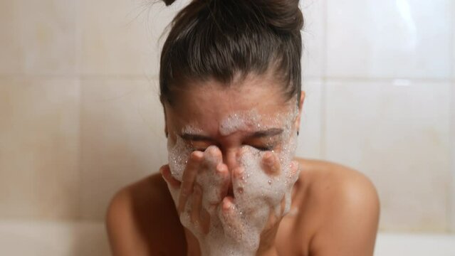 Close up cheerful woman play with foam in light bathroo imn slow motion