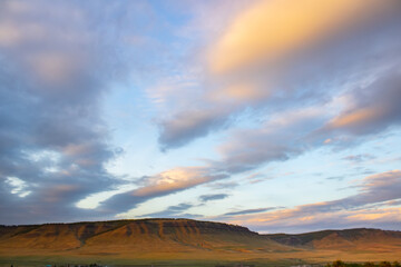Picturesque sky with clouds. Sunset illuminates the mountain range.