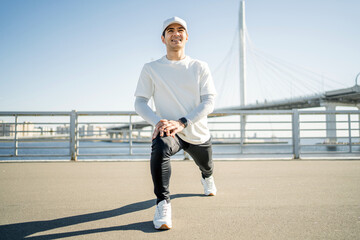 A man conducts a fitness workout in the city, sports comfortable clothes, a smart electronic watch on his hand