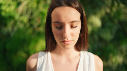 Naklejka premium Portrait of young woman with freckles and dark loose hair wearing white top and jeans looks at the camera