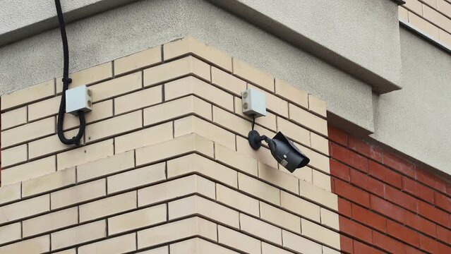 surveillance camera hanging on a brick wall.