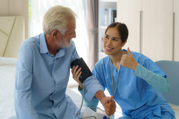 Asian Attentive caregiver using tonometer while elder man having breath problem. Female doctor measuring blood pressure of senior man at home.
