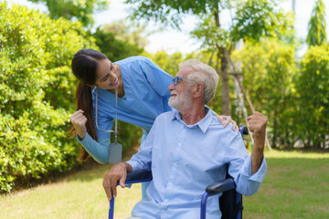 Asian nurse sitting on a hospital bed next to an older man helping hands care in garden at home. Elderly patient care and health lifestyle, medical concept.