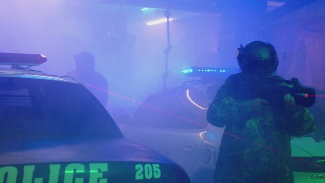 Special Force or police man holding weapon near car flashing lights . Close up view of Police surrounding . Military police or laser tag concept . Shot on ARRI Alexa cinematic camera in slow motion