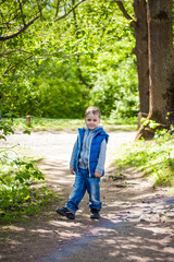 Portrait of a boy in the forest in spring. Take a walk in the green park in the fresh air. The magical light from the sun's rays is left behind. Space for copying. Selective focus.