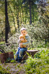 A cute boy is playing with a bear cub in the forest. The sun's rays envelop the space of the clearing with a stump. A magical story of interactions for the book. Space for copying. Selective