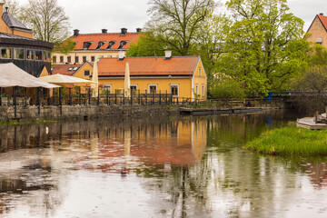 Obraz premium Beautiful view of reflection of city houses and trees in clear calm mirror water on rainy summer day. Sweden.