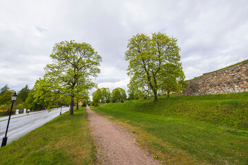 Fototapeta na wymiar Beautiful view in Uppsala city downtown with high stone wall, trees and highway. Sweden.