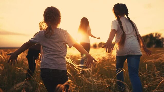 children run in the park at sunset. happy family kids camp kid dream concept. a group of children run on the grass at sunset the rays of the sun silhouette. childhood dream lifestyle teamwork concept