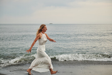 Fototapeta na wymiar a girl in white walks along the seashore