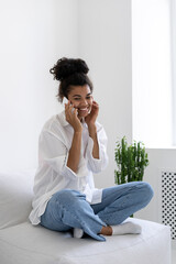 Afro american lady sitting on sofa and talking to phone