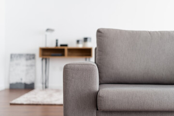 Grey couch in modern apartment against blurred background