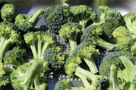 broccoli florets in a stainless steel steam basket