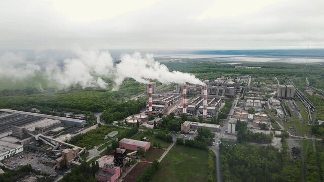 4k footage from a drone flying over a working factory with smoking chimneys