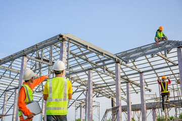 A team of male engineers working at a house construction site. Discuss with the workers and plan...