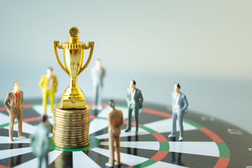 business miniature people standing around gold trophy and stack of gold coin on dartboard hitting in the target center of dartboard  Target business success and investment and finance concepts.