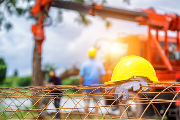 Yellow hard plastic helmet and construction worker gloves placed on the wire in the construction...