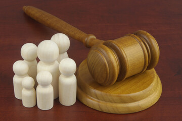 Family law concept. Judge gavel with many wooden figures of family members close-up.