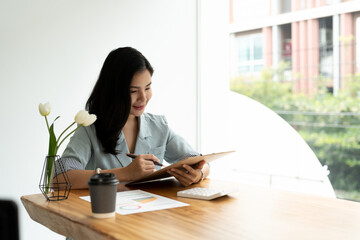 business asian woman working on table using pen point on business paper with financial accounting with growth statistics chart and graph for business analysis with calculator.