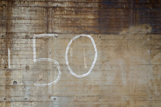 Zahl 50 mit Kreide an eine Wand einer Industrieruine gemalt