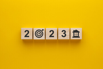 Property in 2023. Wooden cubes with numbers 2023 and house icon on yellow background.