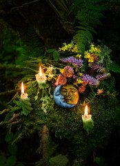 moon amulet, candles, flowers on dark forest natural background. Wiccan, Slavic traditions for...