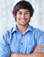 Filled with positivity. A handsome young man standing with his arms folded.