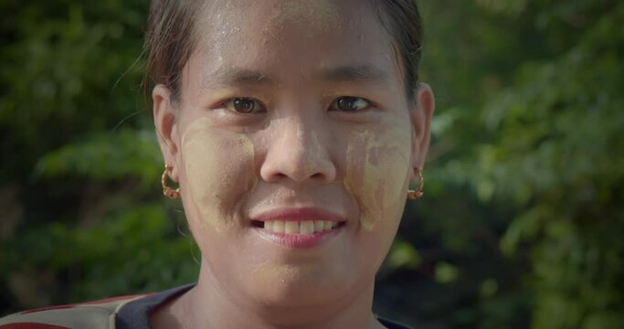 A happy smiling Burmese female farmer woman who powder to their cheeks, known as "Thanaka".