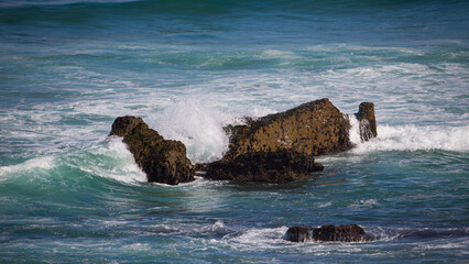 some waves breaking on the rocks in the green sea, Portugal