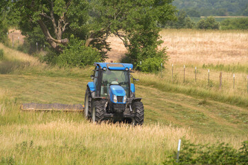 Fototapeta premium Tractor Mowing Hay Grass in a Farm Field