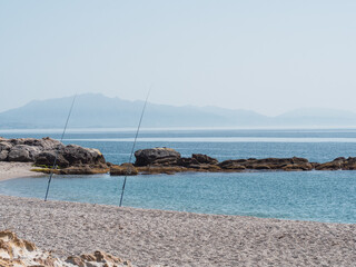 Fishing rods on the shore of the beach in sunny day by the sea. Fishing, relax and vacation concept