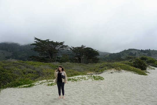 A young woman admiring the beautiful views off endless beach and ocean along the california coast, on a misty morning in Stinson Beach, Northern California, United States