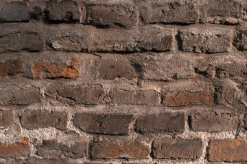 Demaged Rough Brick Wall Surface. Old Brown and Red Brick Wall in the Light of the Setting Sun. Cool Background. Medieval Wall.