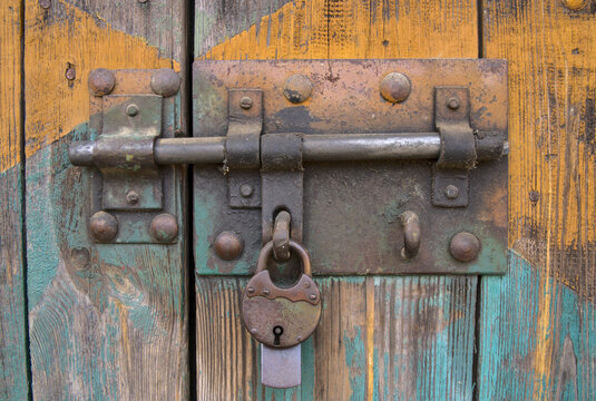 old iron lock on the gate, old wooden planks with shabby paint, close-up detail of a hanging padlock