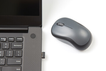 Computer wireless mouse next to a laptop on a white table close-up. electronic personal industry