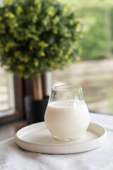 Obraz na płótnie Canvas A glass of milk on a light plate on a table with a white tablecloth