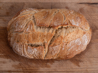 Top down view of a loaf of sourdough bread on a rustic wooden chopping board.