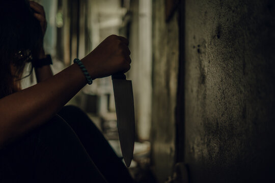 The shadow of a female murderer stood with a knife in a terrifying wasteland, illuminated from behind.Scary horror or thriller movie mood or nightmare at night Murder or homicide concept.
